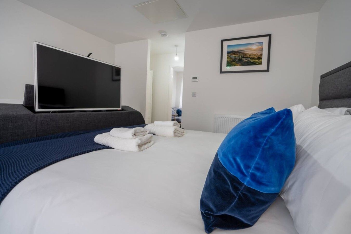Een hotelkamer met een bed, een flatscreen televisie, een ingelijst kunstwerk aan de muur en een raam.