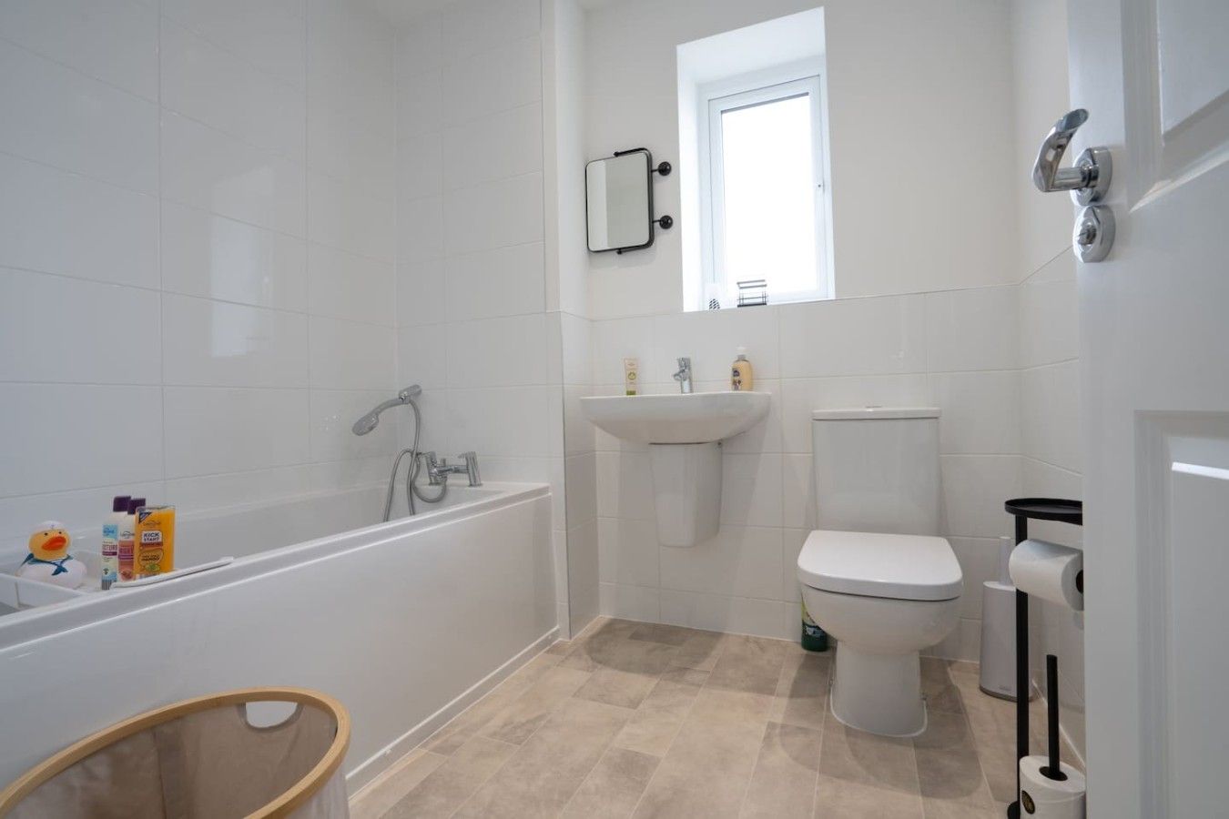Ein Badezimmer mit Badewanne, Waschbecken, Toilette und einem kleinen Fenster.