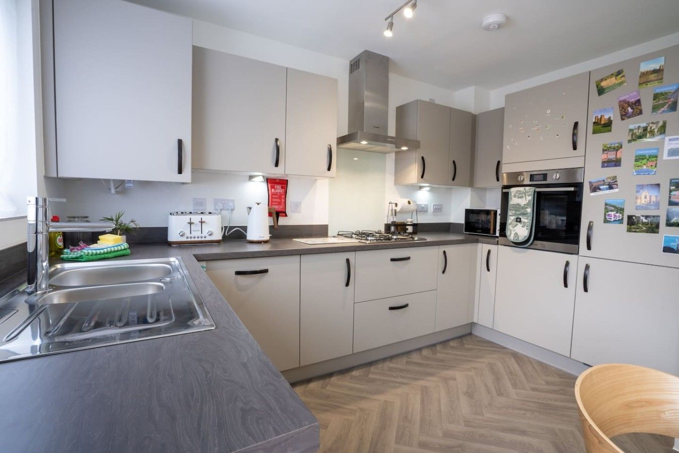 A modern kitchen with stainless steel appliances, a double sink, and a herringbone wood floor.