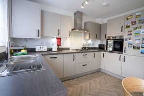 A modern kitchen with stainless steel appliances, a double sink, and a herringbone wood floor.
