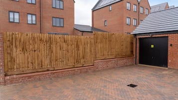 A brick building with a wooden fence, a garage door, and a paved driveway.