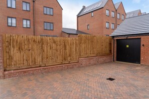 A brick building with a wooden fence, a garage door, and a paved driveway.