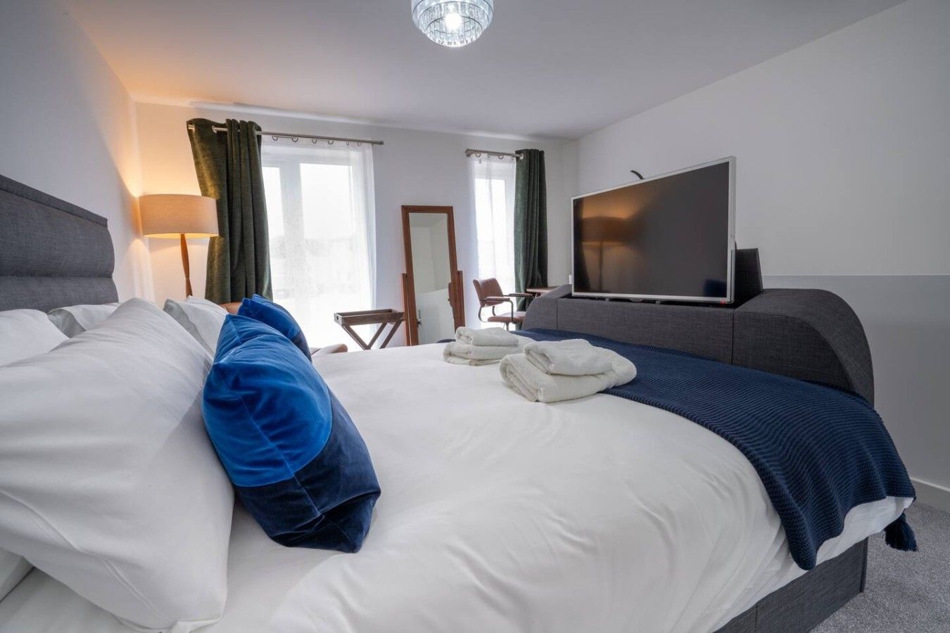 Une chambre d’hôtel avec un grand lit, un téléviseur à écran plat, un bureau et une chaise.