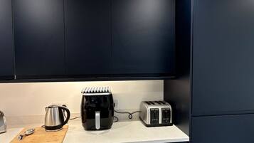 Eine Küche mit dunklen Schränken, einer Kaffeemaschine, einem Toaster und einem Wasserkocher auf der Arbeitsplatte.