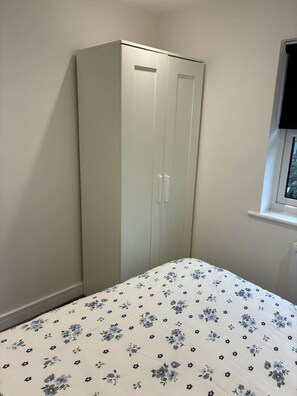 Une chambre avec un lit simple, une armoire et une fenêtre.