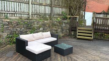 A patio area with a black wicker sofa and a matching ottoman.