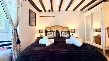 A bedroom with a large bed, two bedside tables, a wardrobe, and a window with curtains.