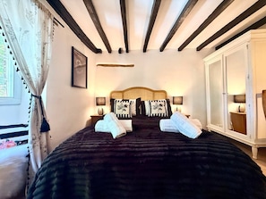 A bedroom with a large bed, two bedside tables, a wardrobe, and a window with curtains. - Wind in the Willows Moreton in Marshes (Gloucestershire)