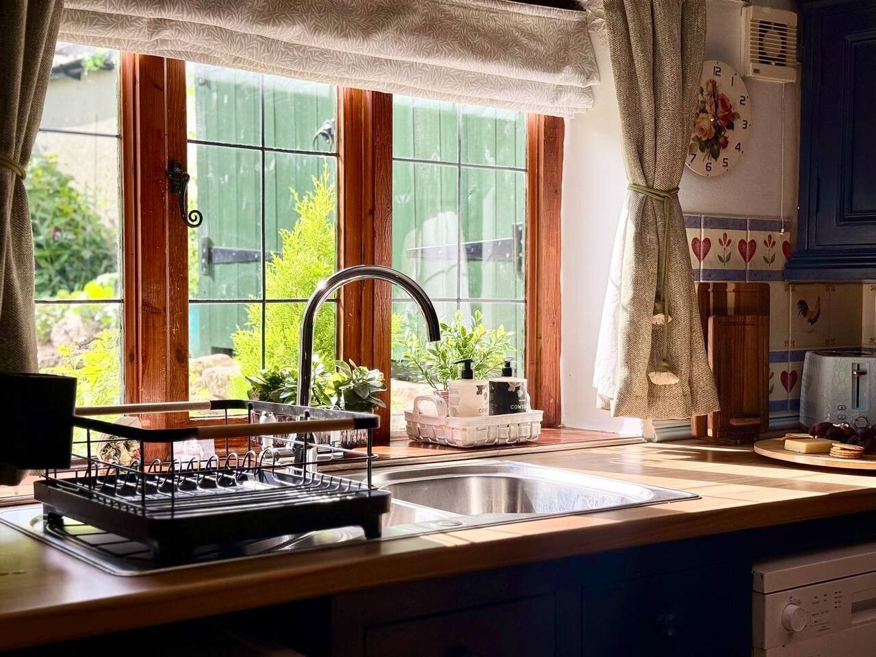 Una cucina con una finestra, un lavandino e un espositore per piatti.