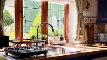 Una cucina con una finestra, un lavandino e un espositore per piatti.
