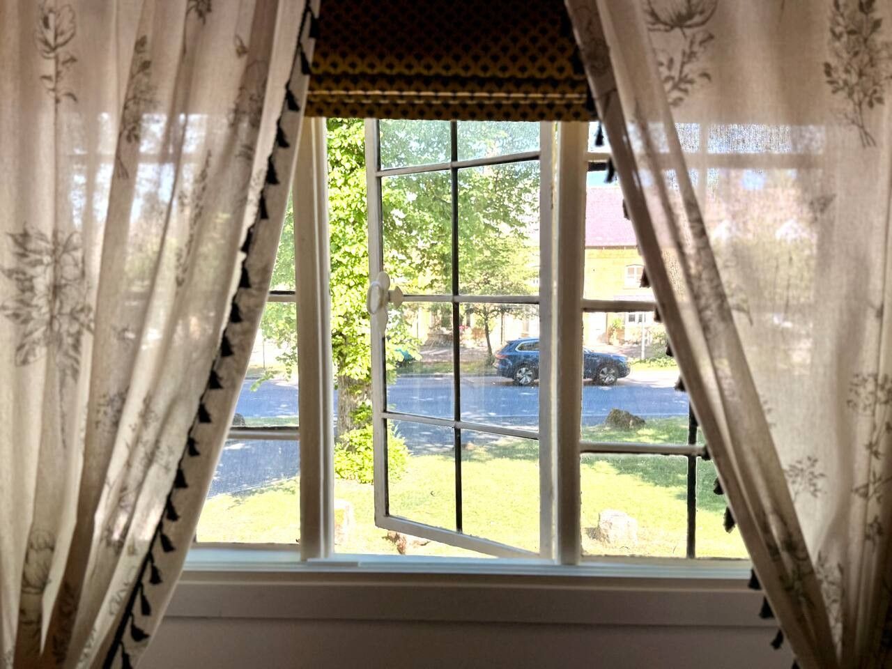 A window with a view of a street and parked cars.