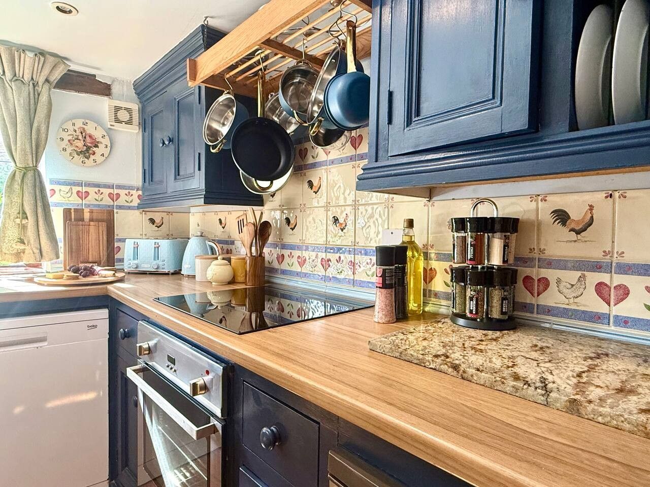 A kitchen with blue cabinets, a stove, an oven, and a countertop with various kitchen items.