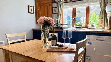 A dining table with a bottle of champagne, two glasses, and a plate with cheese and crackers.