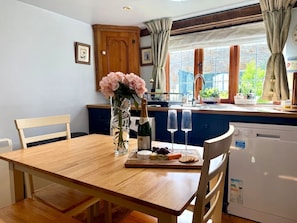 A dining table with a bottle of champagne, two glasses, and a plate with cheese and crackers. - Wind in the Willows Moreton in Marshes (Gloucestershire)