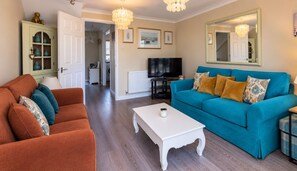 A living room with a sofa, a coffee table, and a television. - The Hideaway - with free parking! (West Sussex)