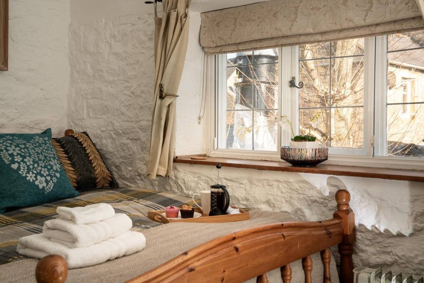 A cozy room with a bed, a window with a view, and a shelf with a plant.
