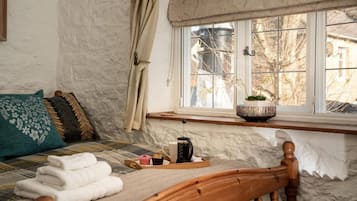 A cozy room with a bed, a window with a view, and a shelf with a plant.