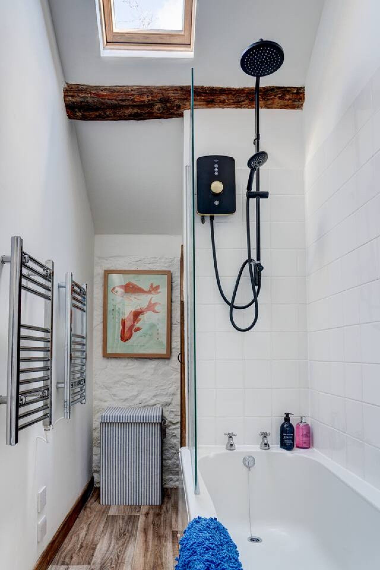 Et badeværelse med ovenlys, bruser, badekar og en radiator.