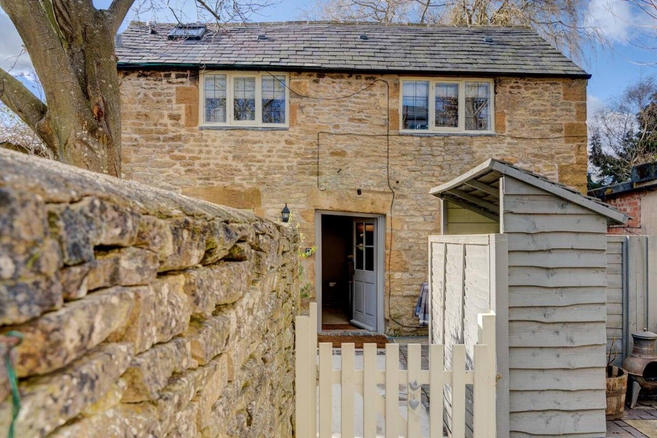 A stone house with a wooden door and a small shed.