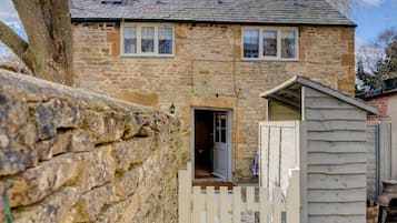 A stone house with a wooden door and a small shed.