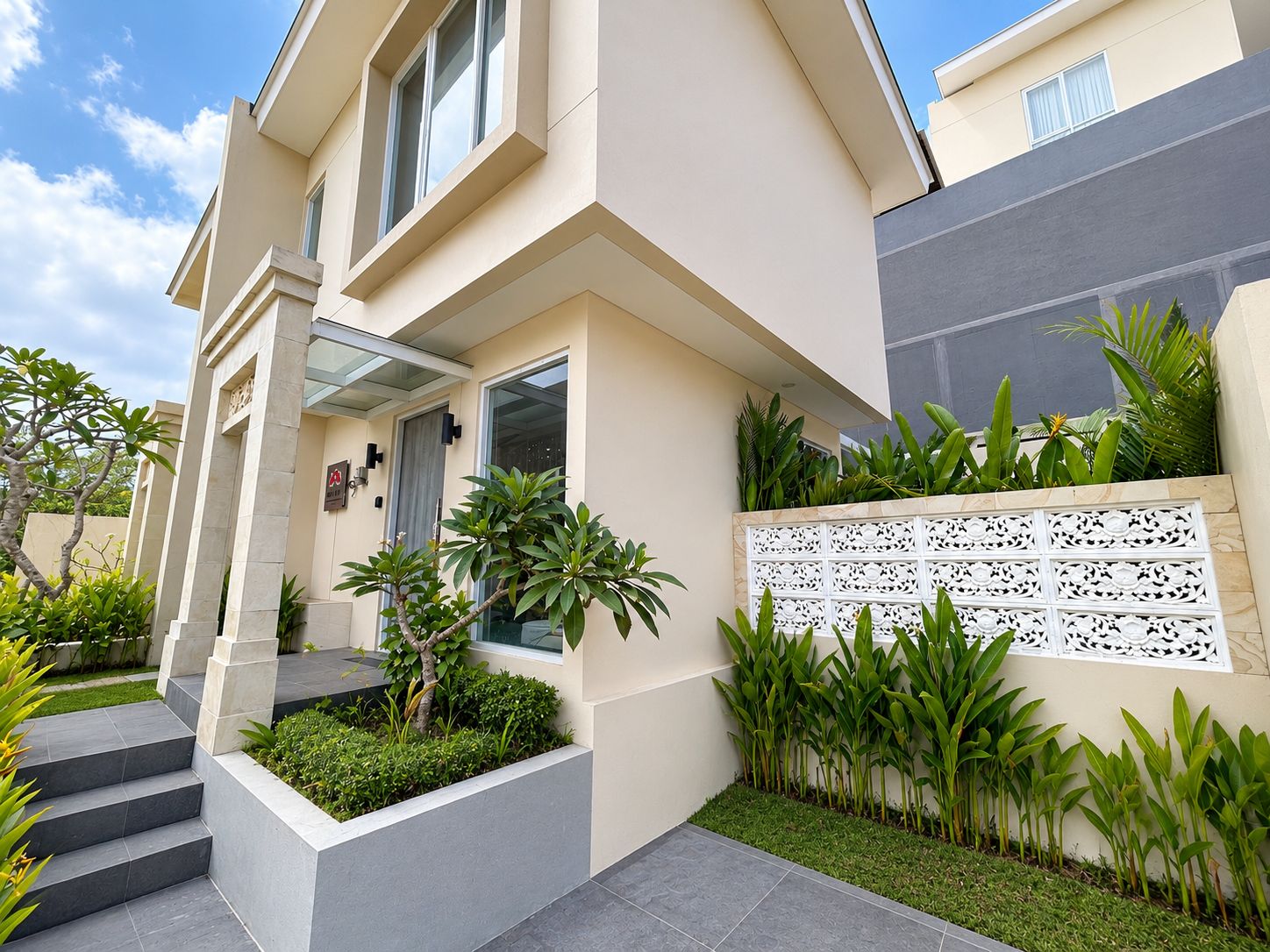 A modern residential building with a flat roof, a balcony, and a decorative white wall panel.