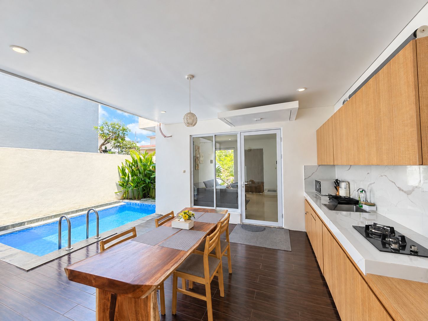 A modern kitchen with a built-in stove, wooden cabinets, and a dining area with a table and chairs.