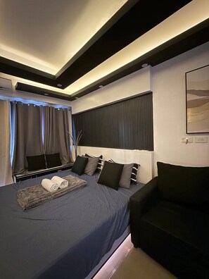 A modern bedroom with a large bed, a seating area, and a painting on the wall. - 1 BR Unit near MOA SMX WTC NAIA Manila Bay (Pasay City)