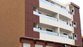 Un immeuble à plusieurs étages, doté d’une façade sobre, de nombreux balcons et d’un magasin au rez-de-chaussée.