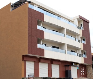 A multi-story building with a flat facade, multiple balconies, and a storefront at the ground level. - Residence Nehemie (Abidjan)