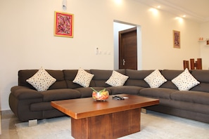 A living room with a brown sofa, a wooden coffee table, and a colorful abstract painting on the wall. - Residence Nehemie (Abidjan)