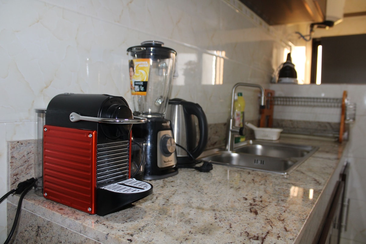 A kitchen with a coffee maker, a blender, and a kettle.