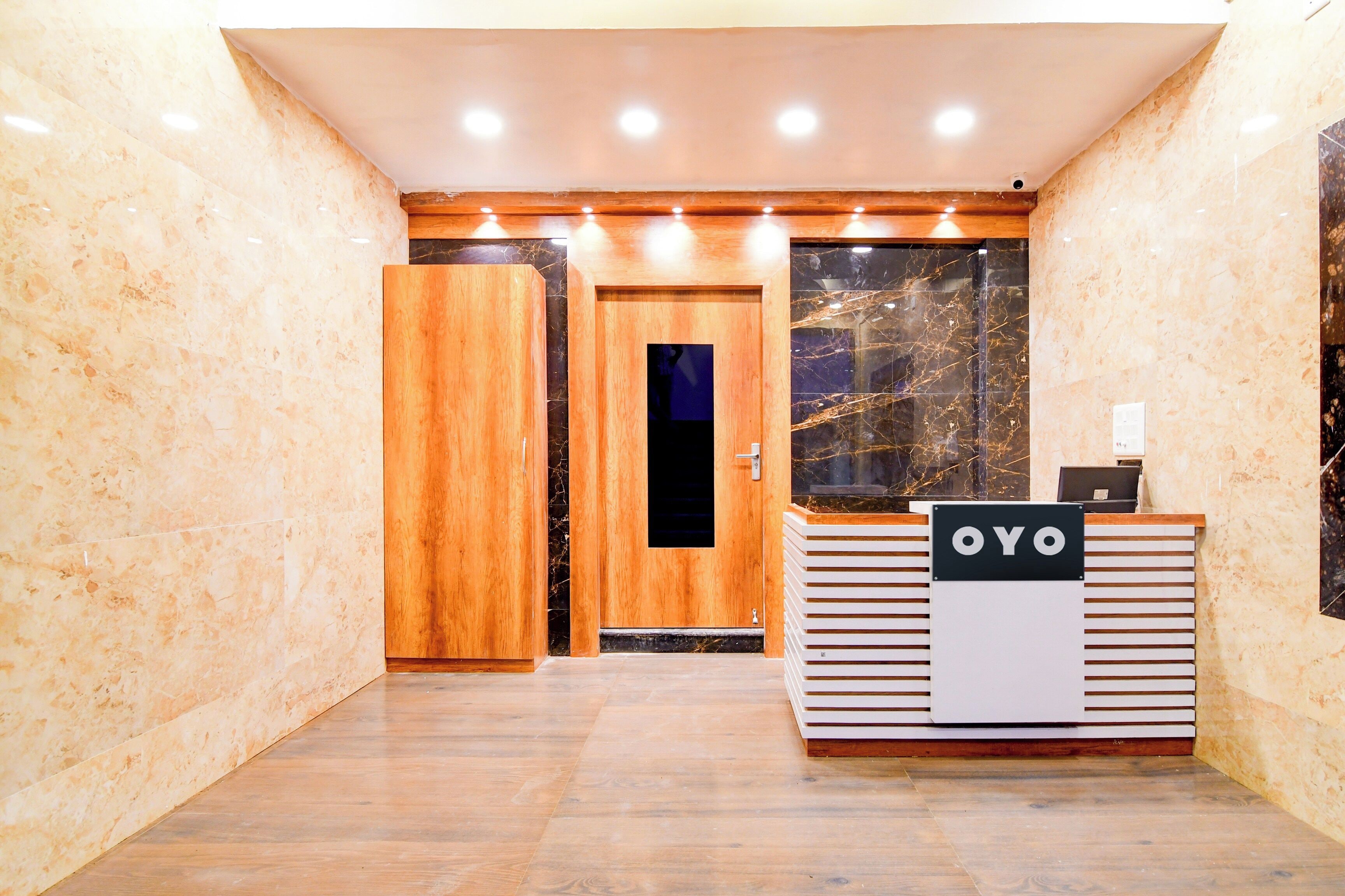 A reception area with a wooden door, a reception desk with a sign, and marble walls.