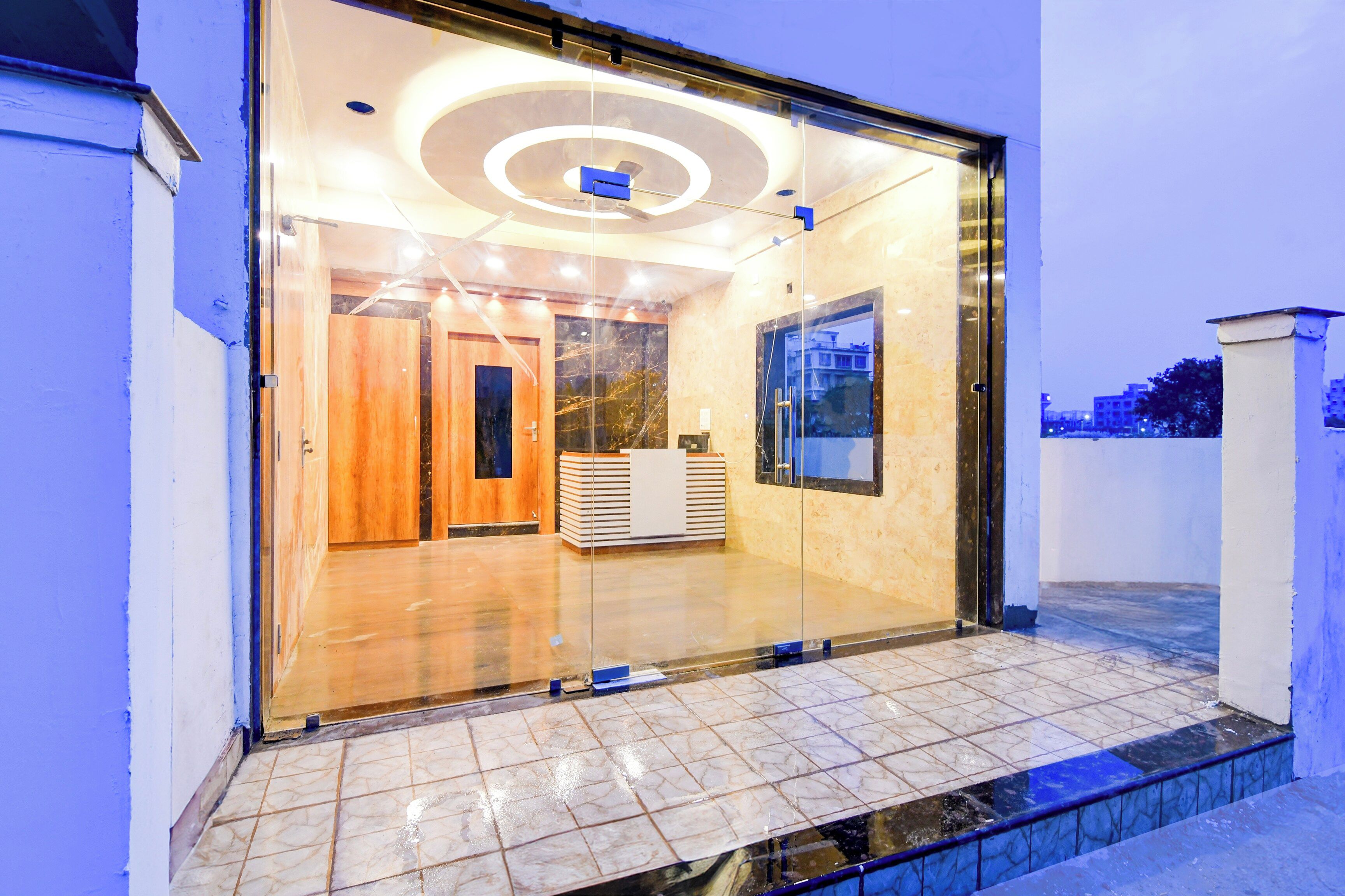 A modern building entrance with a glass door, a reception desk, and a tiled floor.