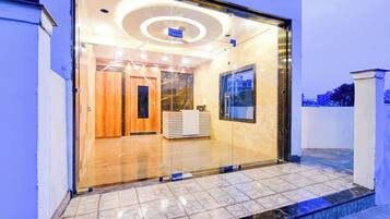 A modern building entrance with a glass door, a reception desk, and a tiled floor.