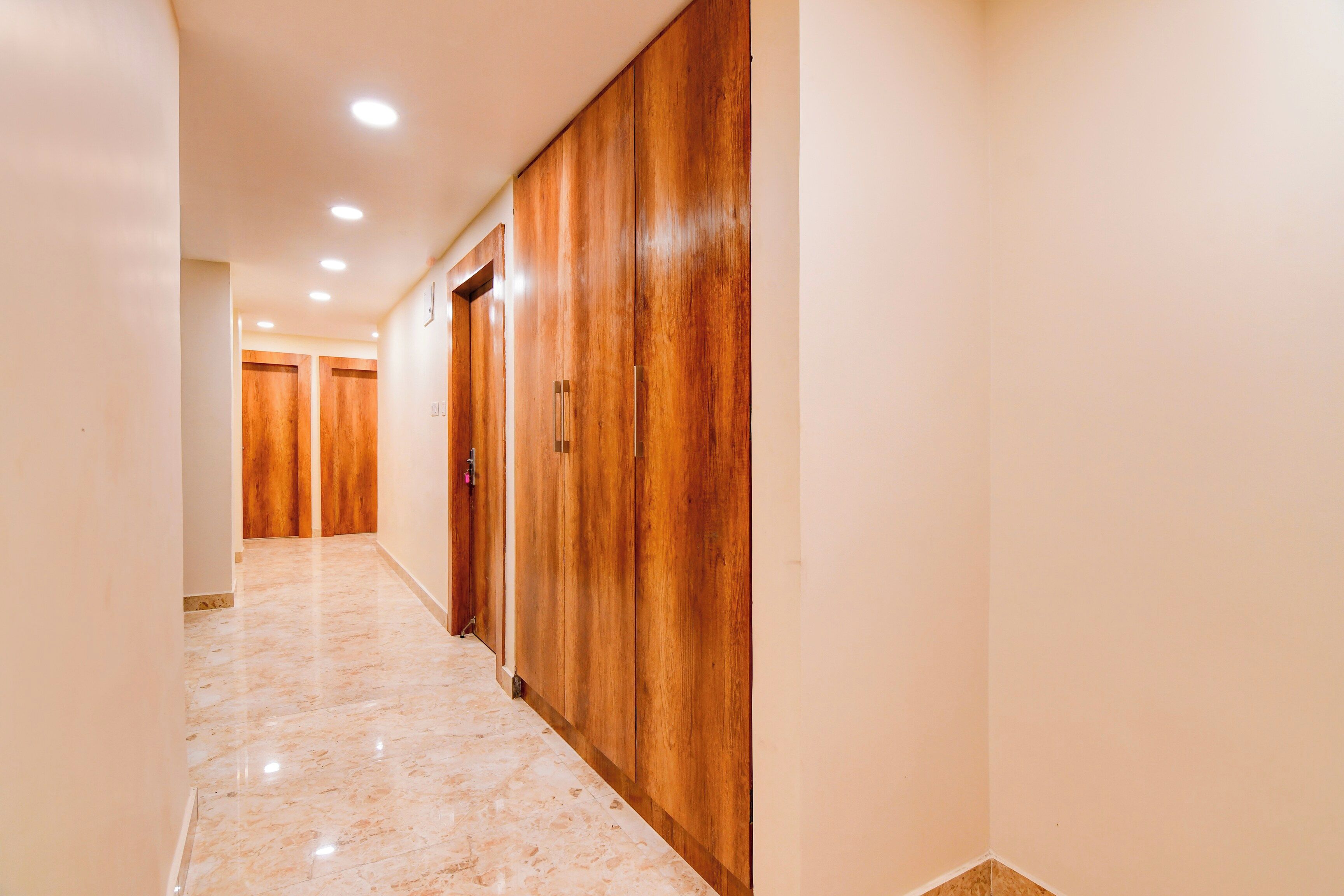 A hallway with wooden doors and a marble floor.