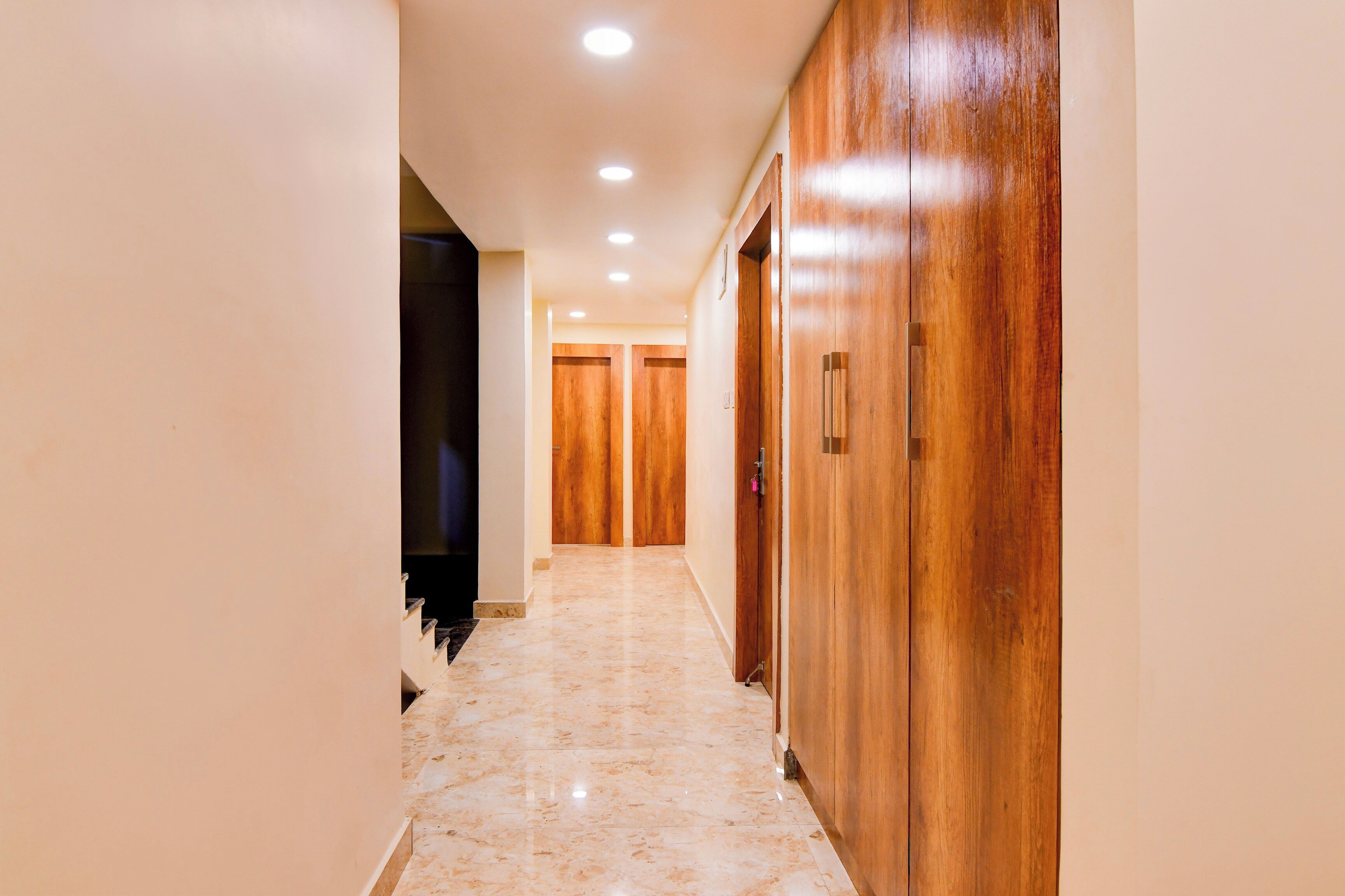 Un pasillo con puertas de madera y piso de baldosas.