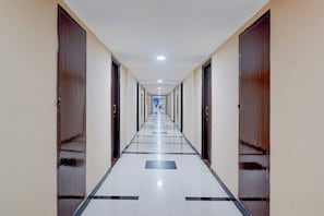 Un largo y estrecho pasillo de hotel con puertas a ambos lados, que conduce a habitaciones individuales.