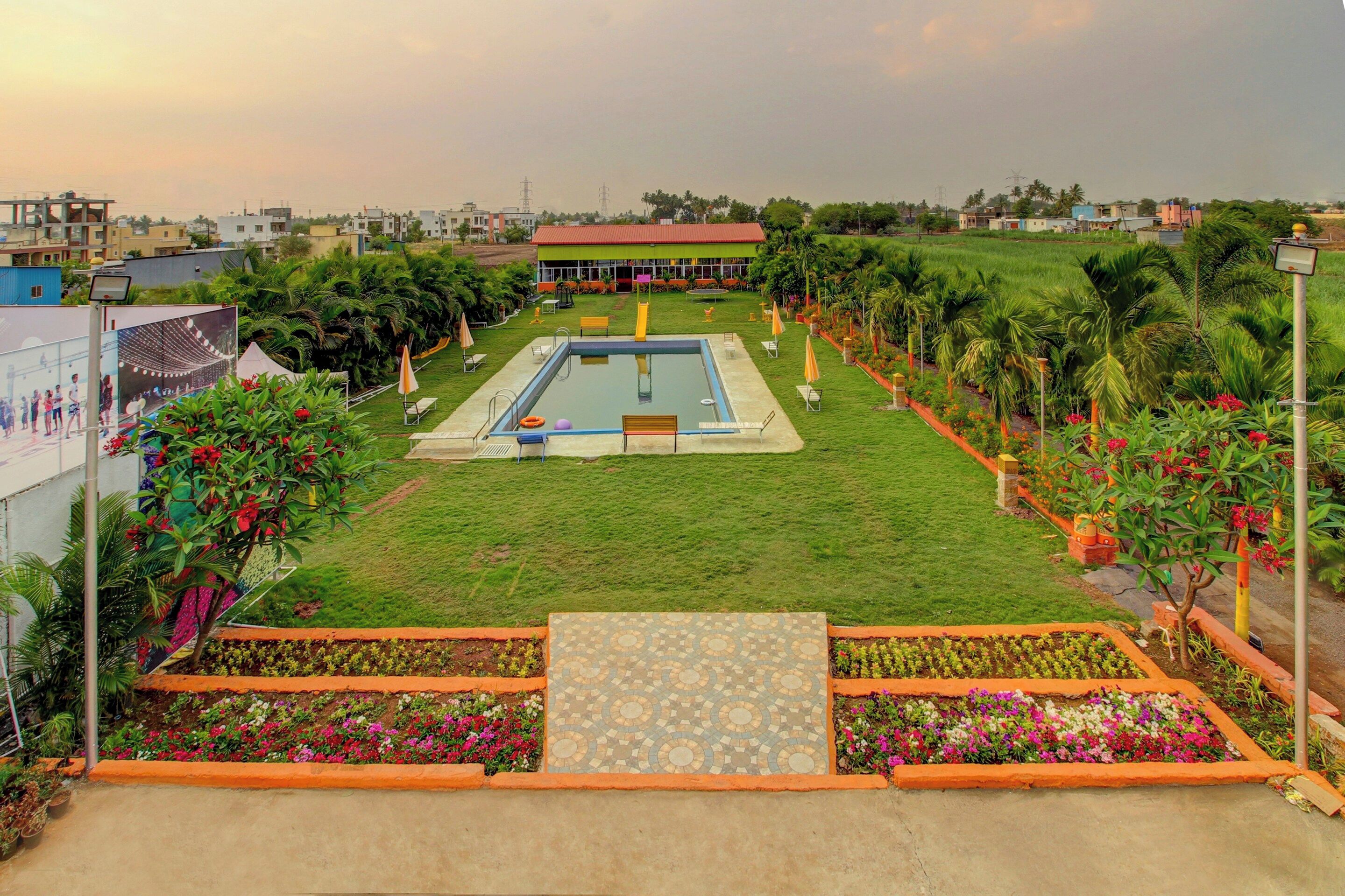 A swimming pool with a tiled deck, surrounded by a well-maintained lawn and flower beds.