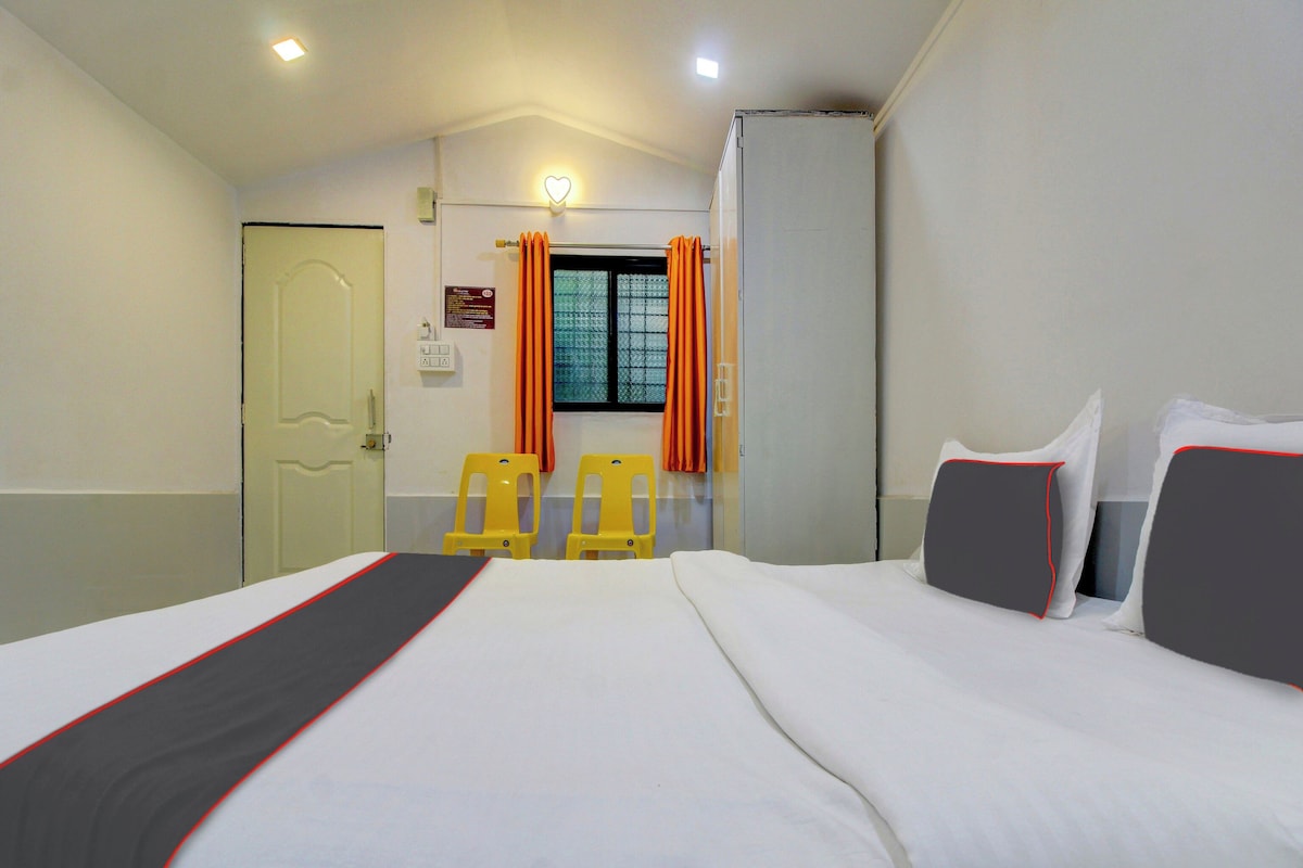 Una habitación de hotel con una cama, dos sillas, un armario y una ventana con cortinas.