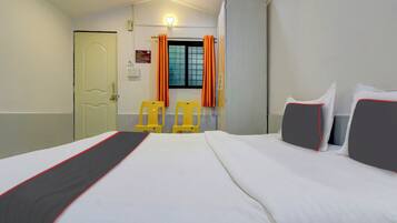Una habitación de hotel con una cama, dos sillas, un armario y una ventana con cortinas.