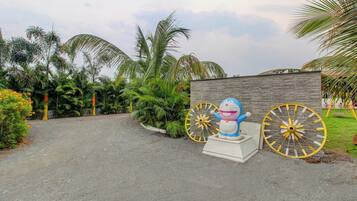 A paved pathway leading to a building with a decorative statue of a cartoon character and two large decorative wheels.