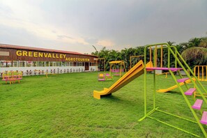 A playground with slides and swings, a building with 'GREEN VALLEY AGRICULTURISM' signage, and a grassy area.