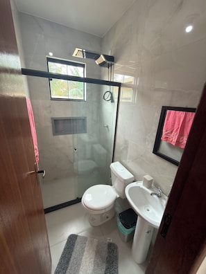 A modern bathroom with a glass-enclosed shower, a toilet, and a sink. - New Listing (Cabo Frio)