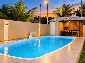 En swimmingpool med ett vattenfall och en omgivande mur som har inbyggd belysning.