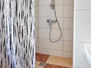 A bathroom with a shower, tiled walls, and a patterned curtain. - Settle Into Vienna 1BR Long Stay (Wien)