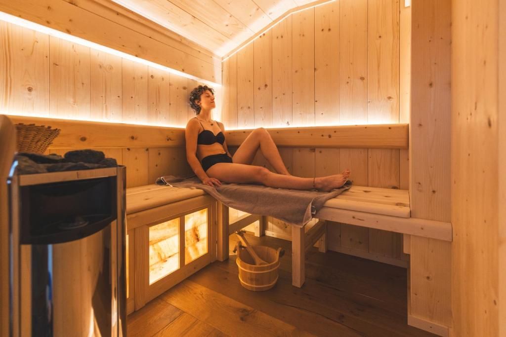 A sauna room with wooden benches and benches, a wooden bucket, and a towel.