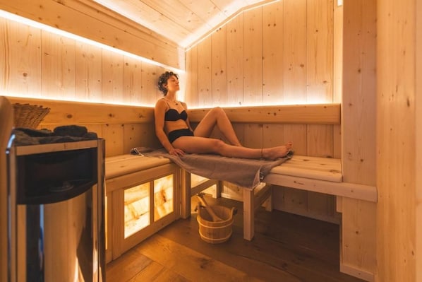 A sauna room with wooden benches and benches, a wooden bucket, and a towel.