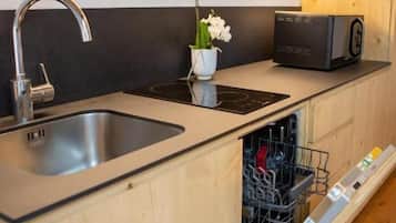 Una cocina con lavavajillas integrado, un lavamanos de acero inoxidable y armarios de madera.
