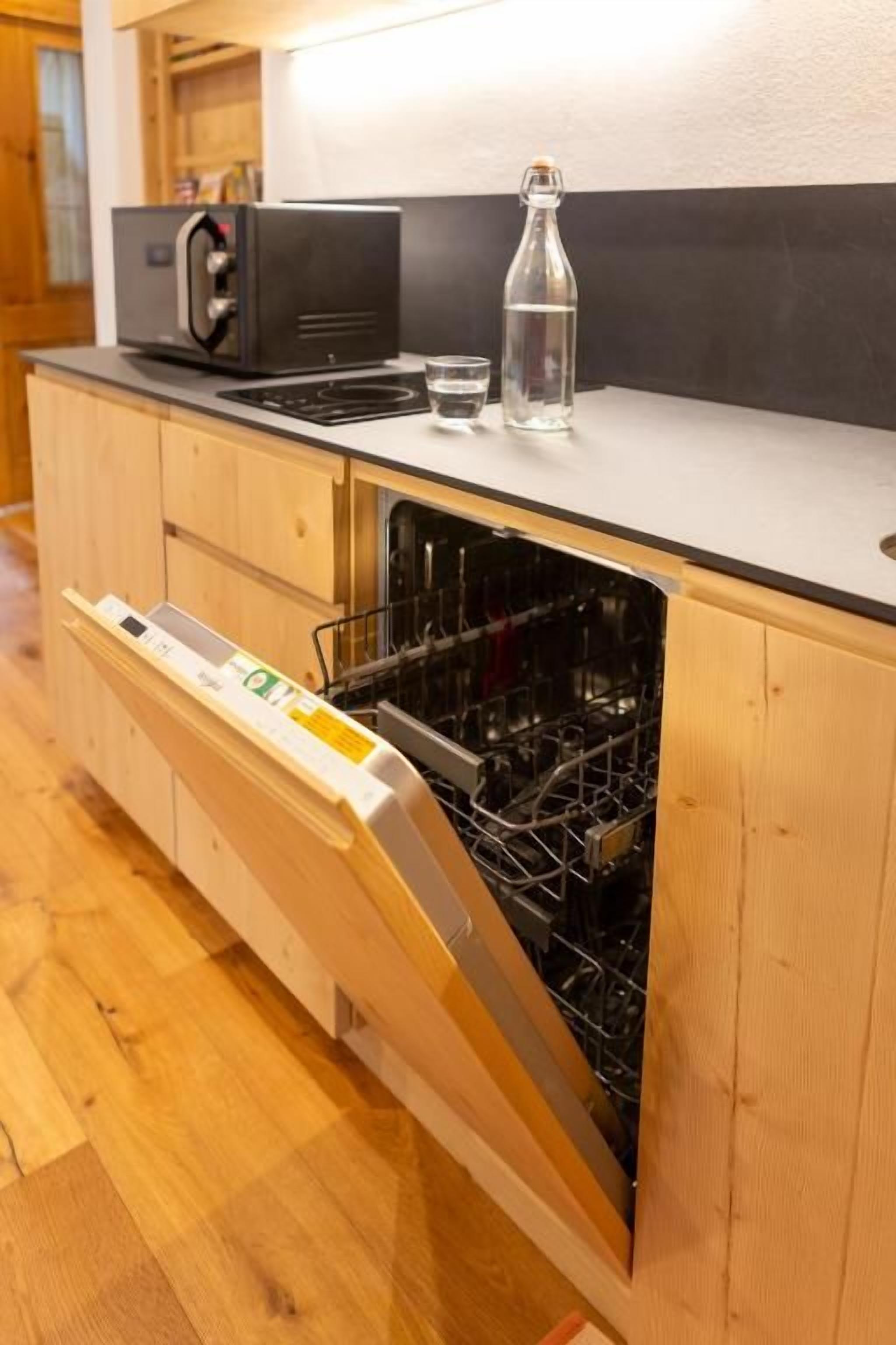 Una cocina con lavavajillas, microondas y una botella de agua sobre la encimera.