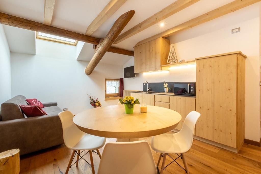 Una cocina moderna con armarios de madera, una mesa de comedor con sillas y un sofá en una sala de estar con techo inclinado.